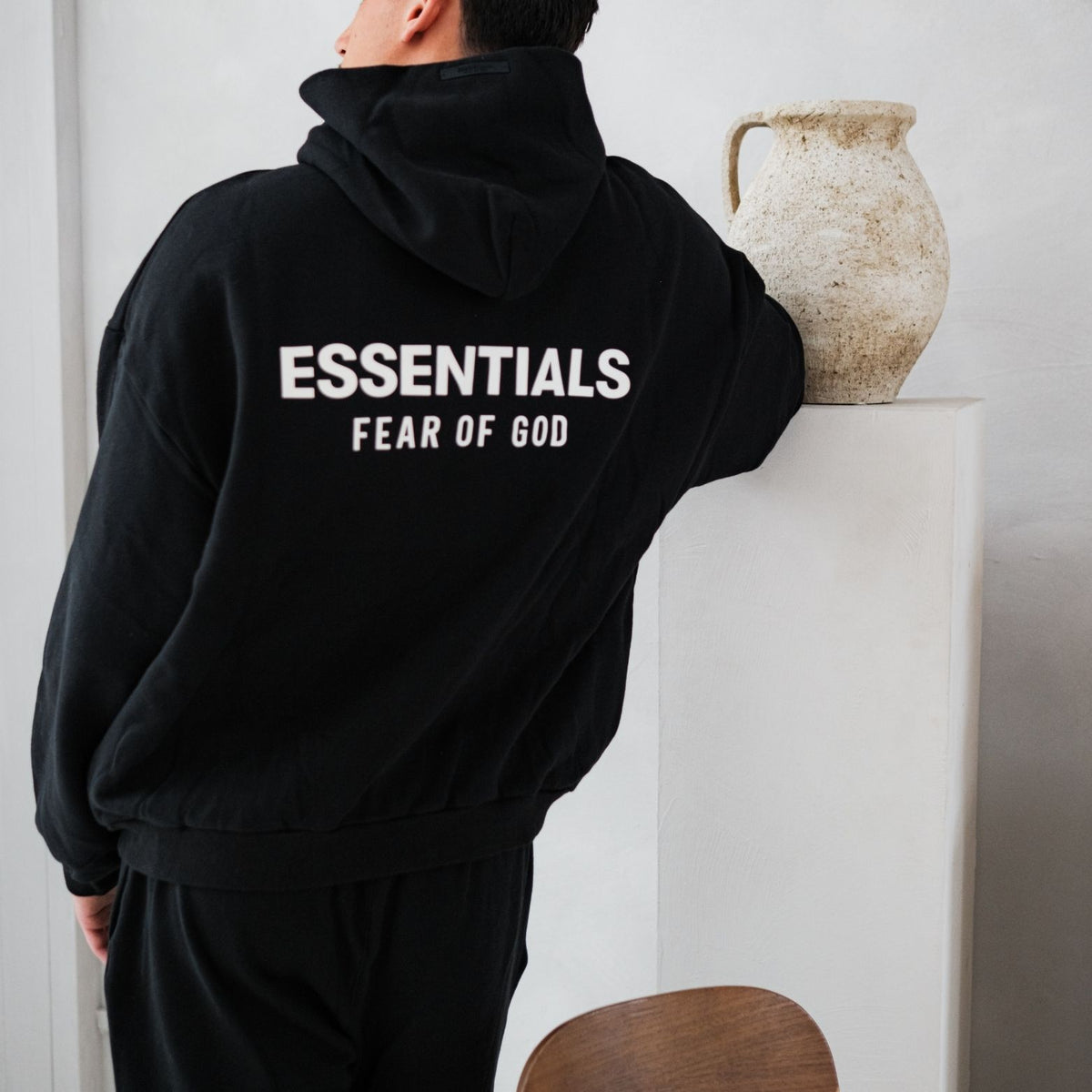 Fear of God Essentials FW24 Black White Full set, achteraanzicht zwarte hoodie met witte tekstprint