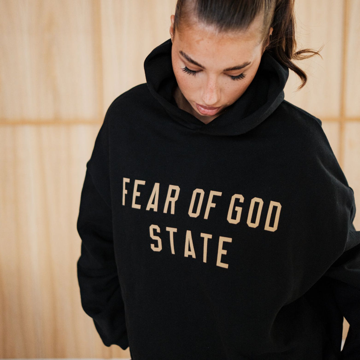 Fear of God Essentials FW24 Black Yellow State Hoodie, vooraanzicht met FEAR OF GOD STATE tekstprint
