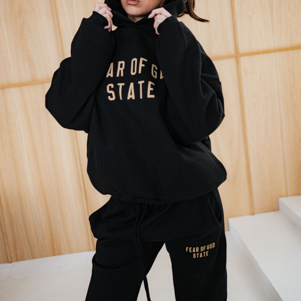 Fear of God Essentials FW24 Black Yellow State Hoodie, driekwart aanzicht met capuchon omhoog